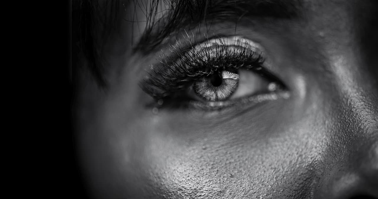 Long lower and upper lashes on a dark eye, in black and white