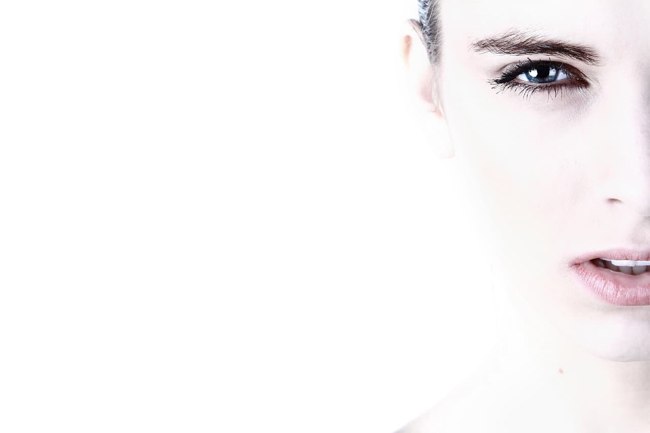 Half a face lit bright white, one dark, cleanly shaped brow above a blue eye