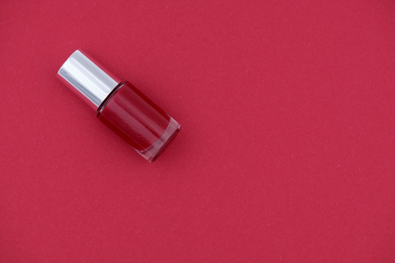A bottle of deep red nail polish on a red ground