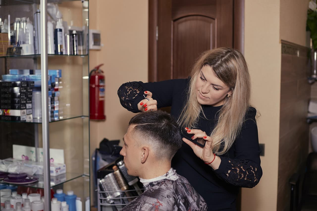 A stylist cutting a client’s hair at the salon chair